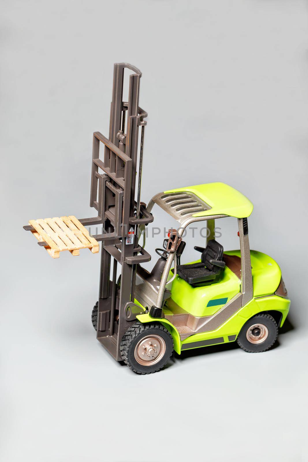 Toy model of an industrial pallet loader on a light gray background. by Sergii