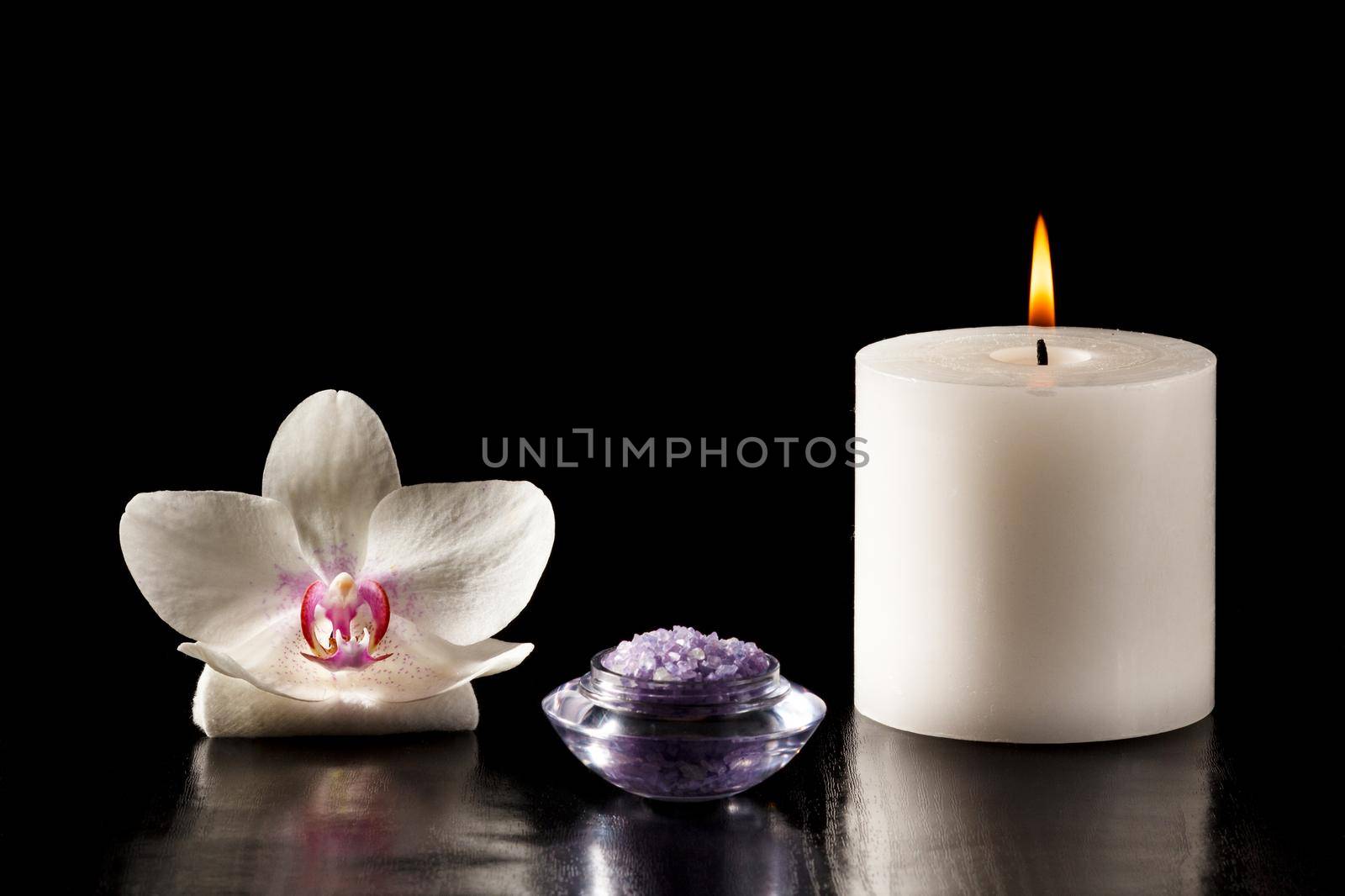 White orchid flower, bowl with sea salt for spa, candle on black background