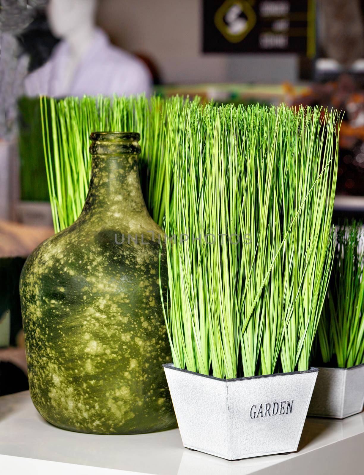 Green grass in a white pot and an old bottle as part of the restaurant's interior decoration. by Sergii