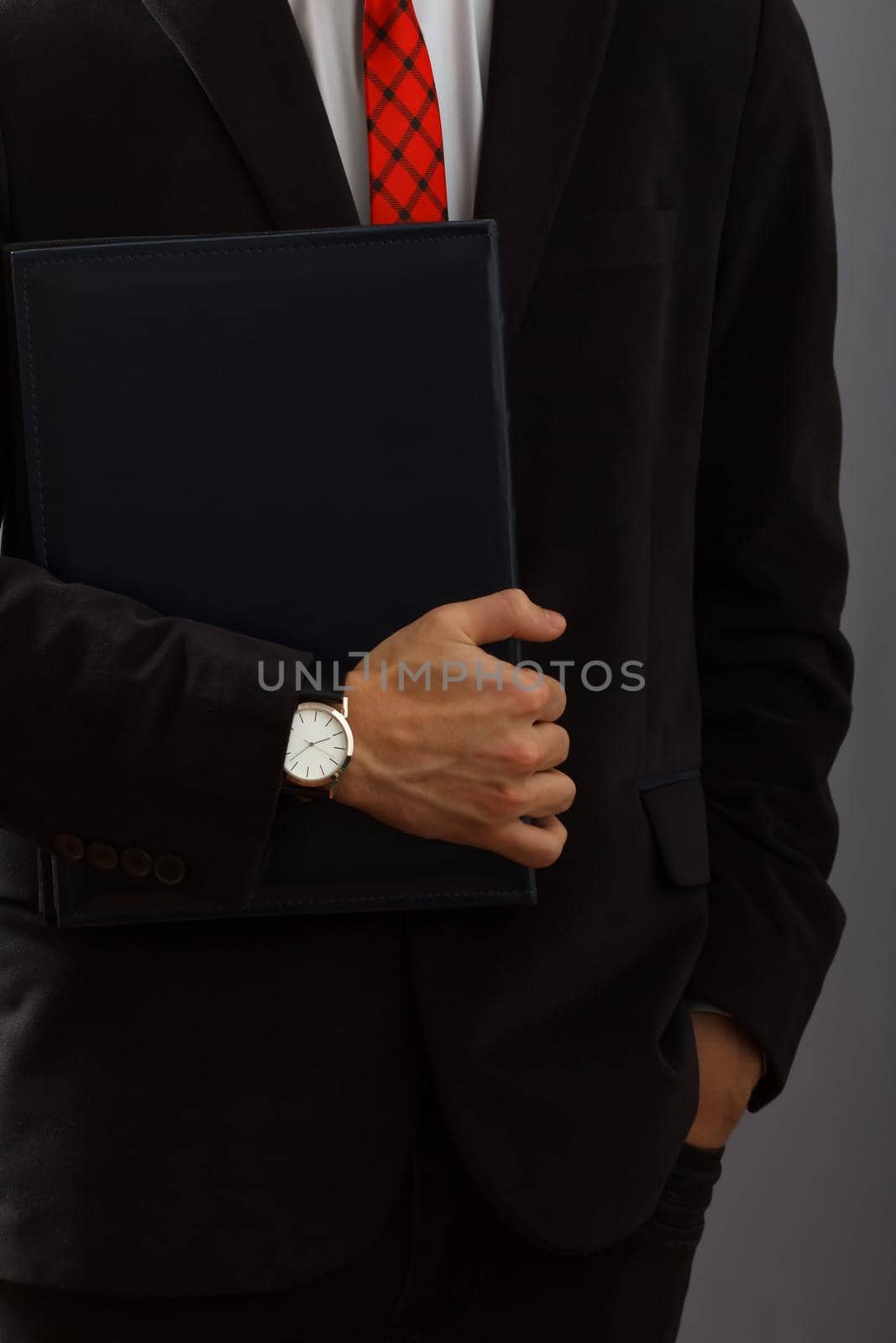 Young man in black suit holding the folder in his hand with wristwatch