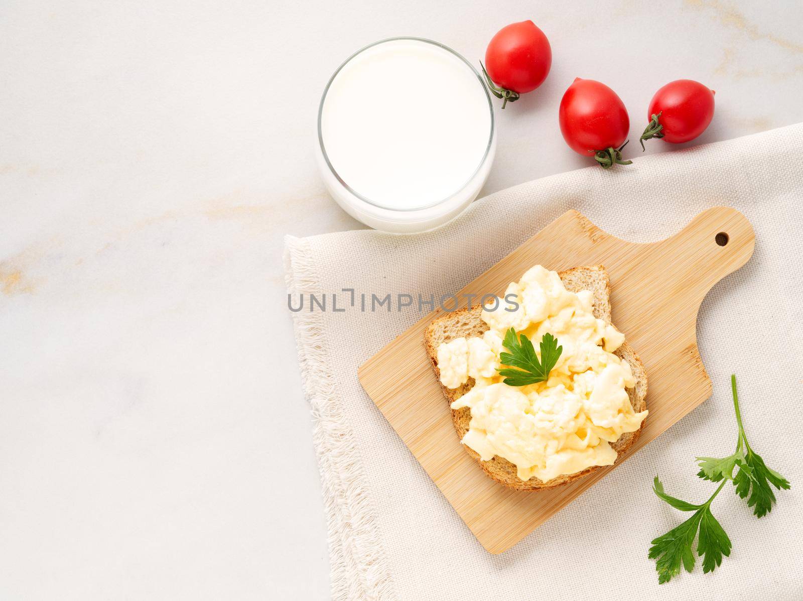 Sandwich with pan-fried scrambled eggs on a wooden cutting board, top view, copy space