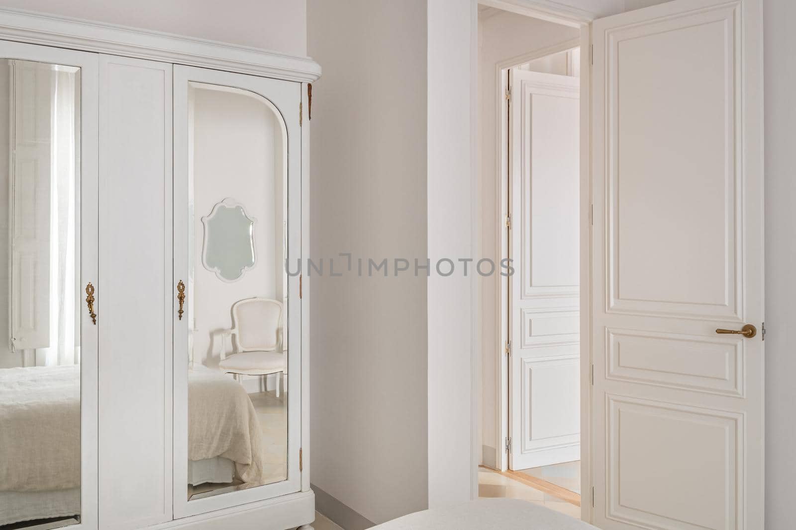 Interior of classic style bedroom. Vintage wardrobe with mirrors and cozy bed in reflection