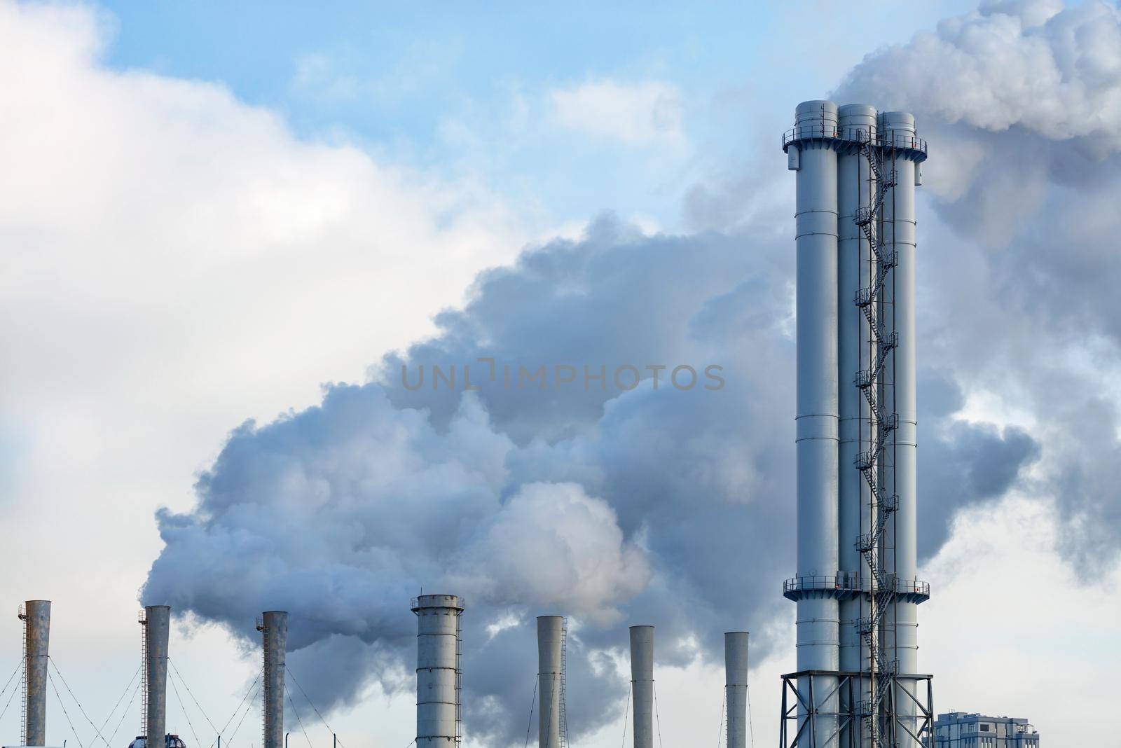 Smoking chimneys from the city thermal station against the background of the winter sky during the heating season, copy space.