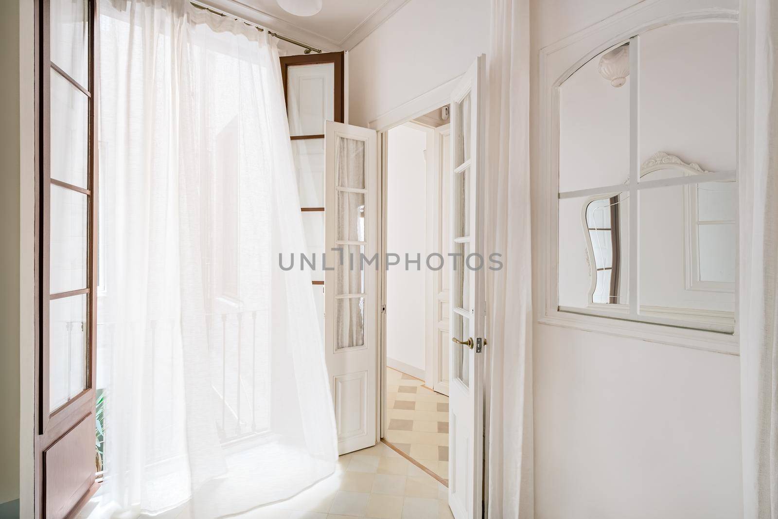 White waving curtain in empty room of refurbished apartment in Barcelona. Classic style interior with window and mirror. by apavlin