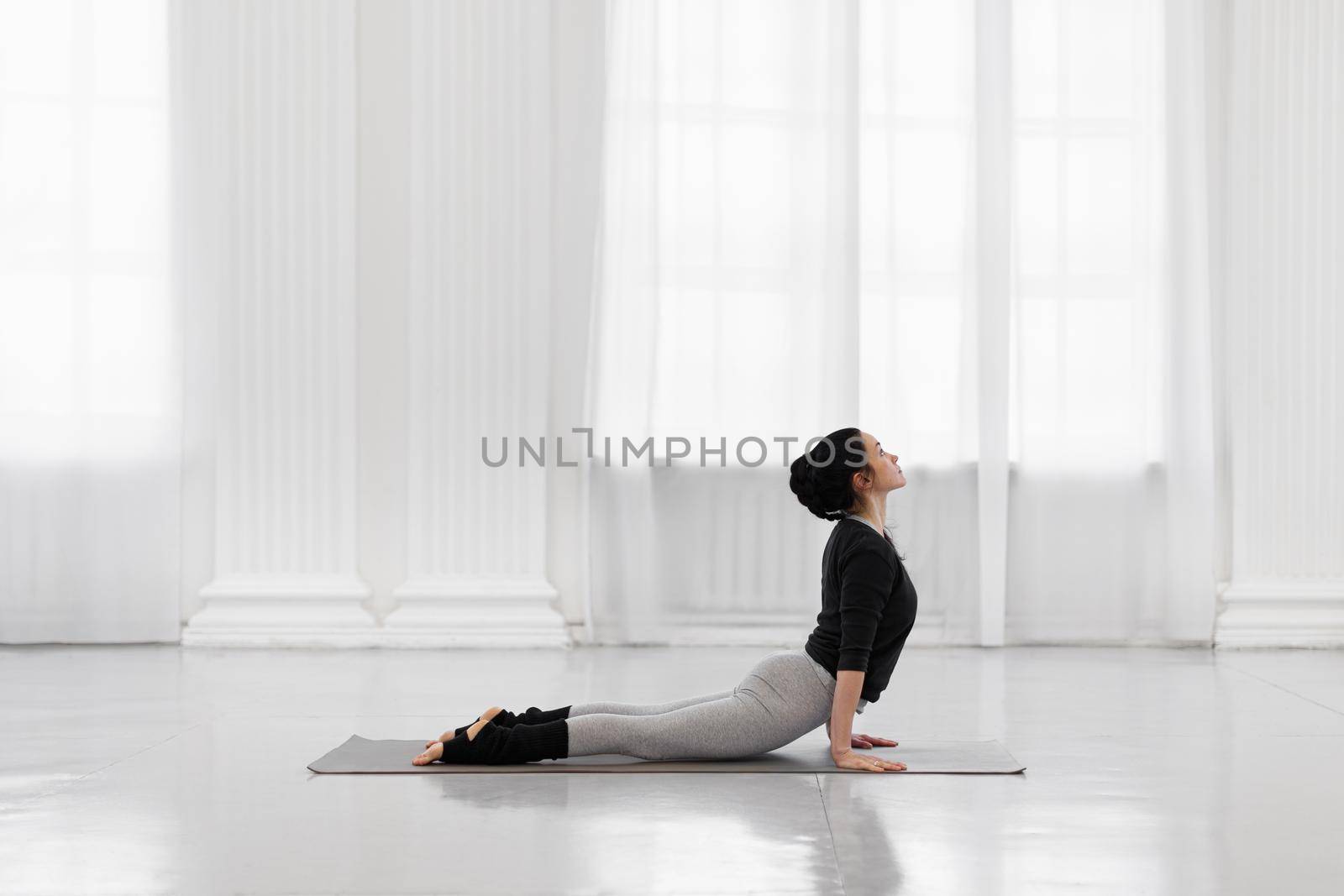 Cobra Pose. Beautiful young asian woman practicing yoga pose on gray mat at yoga studio. by apavlin