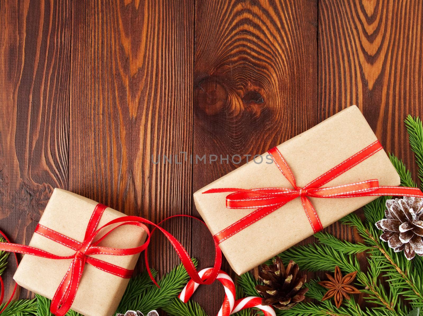 Christmas and Happy New Year dark brown background. Gift Christmas box, fir branches, a wooden table, top view, copy space