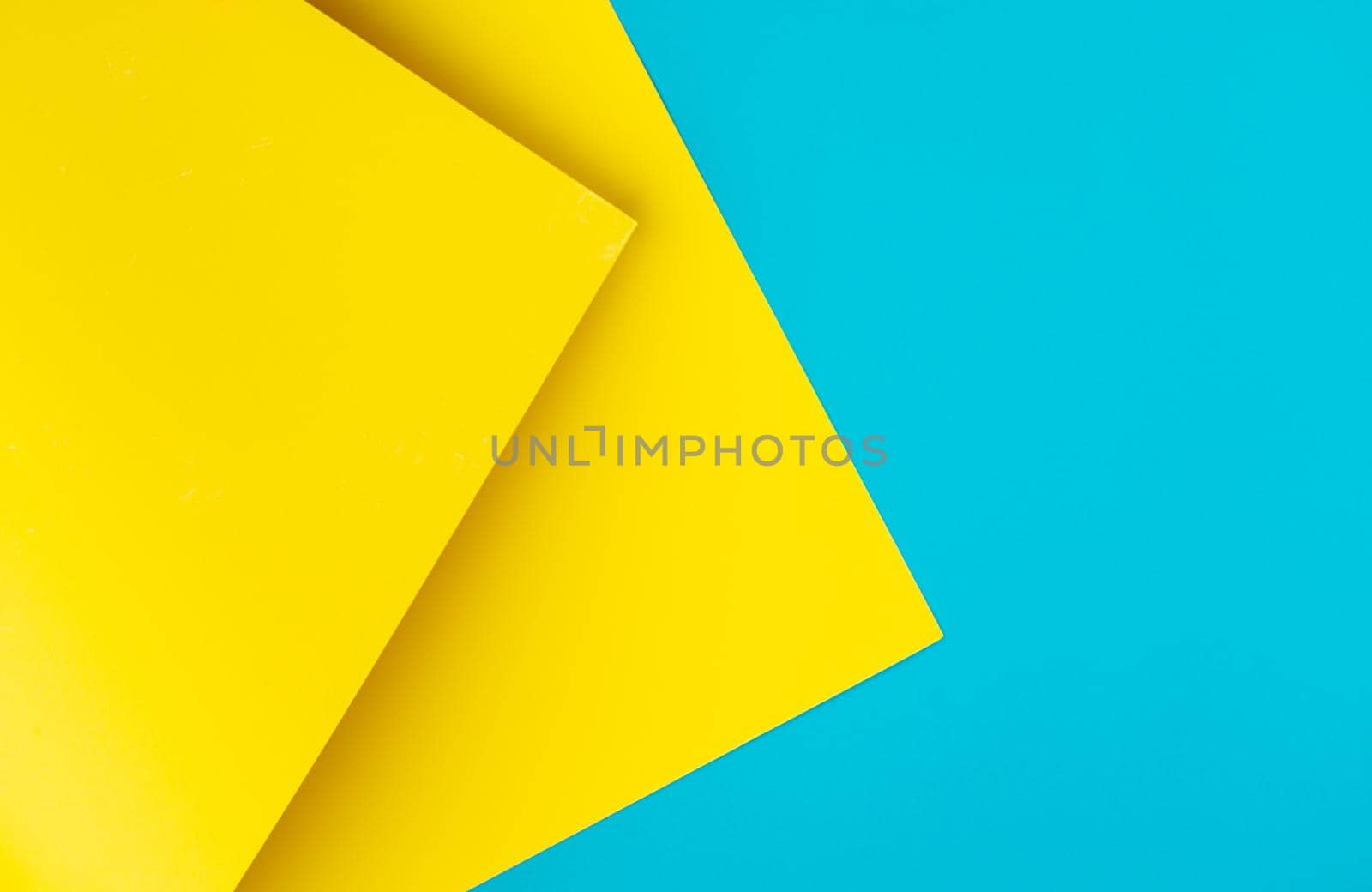 Yellow and blue colored background of overlapped cardboard layered geometric shaped sheets. Abstract design concept. Surface elements. Shredded texture, craft backdrop