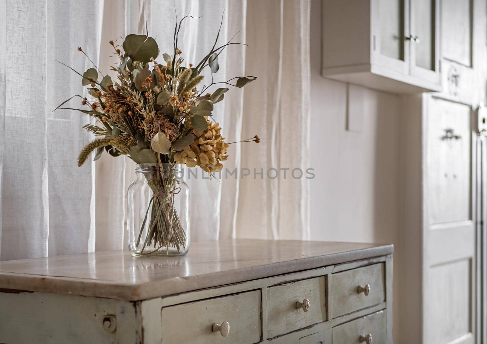 A bouquet of dry flowers in a hallway of the retro style decorated apartment with old style furniture