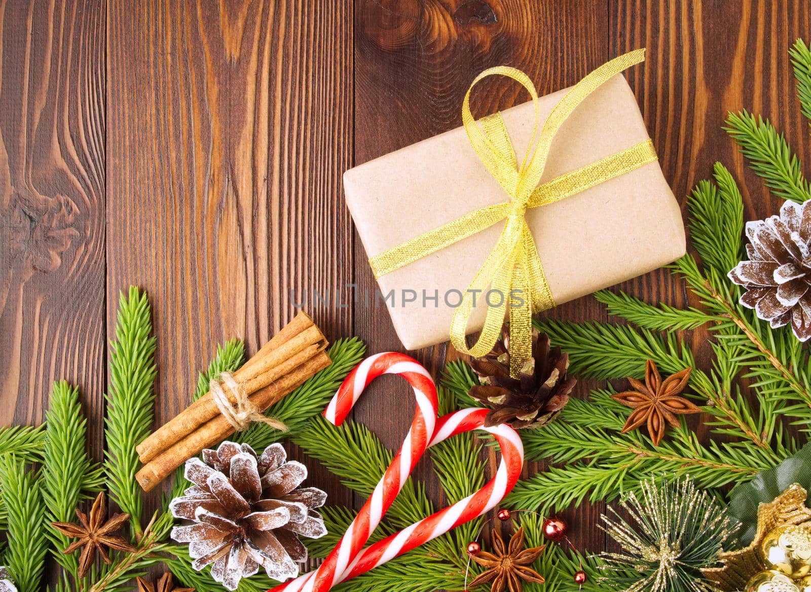 Christmas and the Happy New Year background. Gift Christmas box of Kraft paper, fir branches, cones, cinnamon, wooden table.