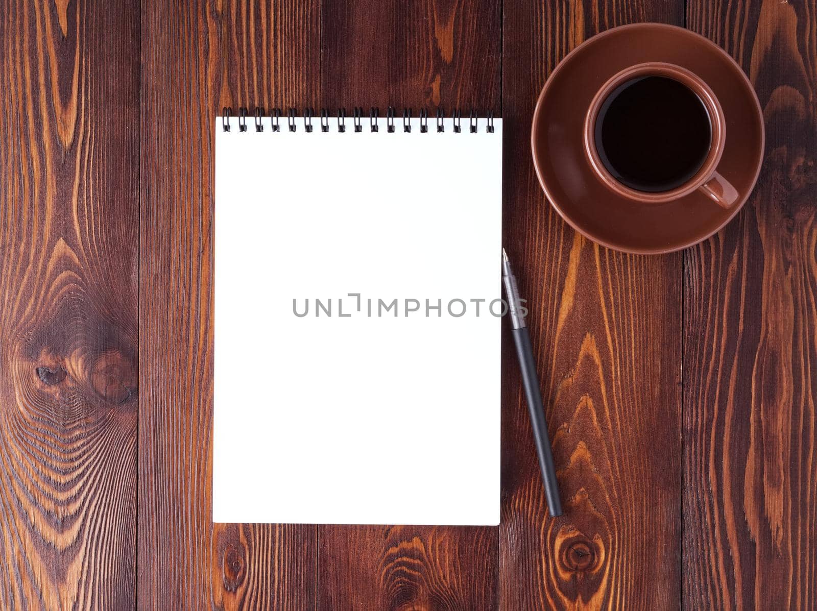 open notepad with spiral, pen and coffee cup on dark brown wooden table, top view by NataBene