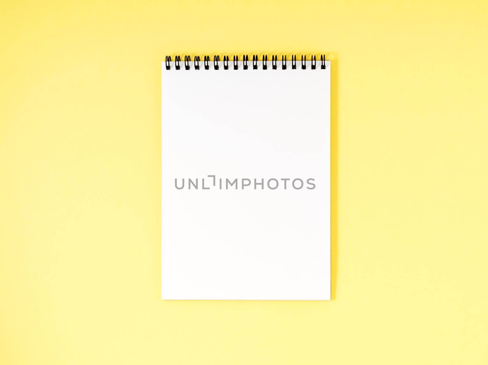 Blank notepad white page on yellow desk, a color background. Top view, empty space for text.