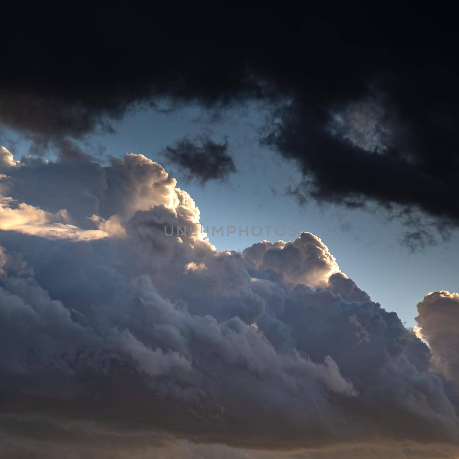 Confrontation of light and darkness. Clouds lighted with sun versus dark overhanging heavy clouds. Dramatic sky at sunset. by apavlin