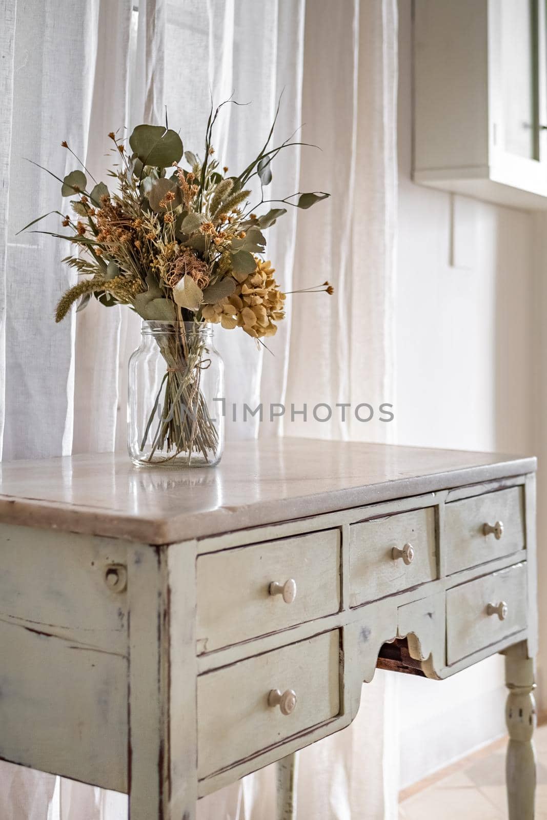 A bouquet of dry flowers in a hallway of the retro style decorated apartment with vintage furniture