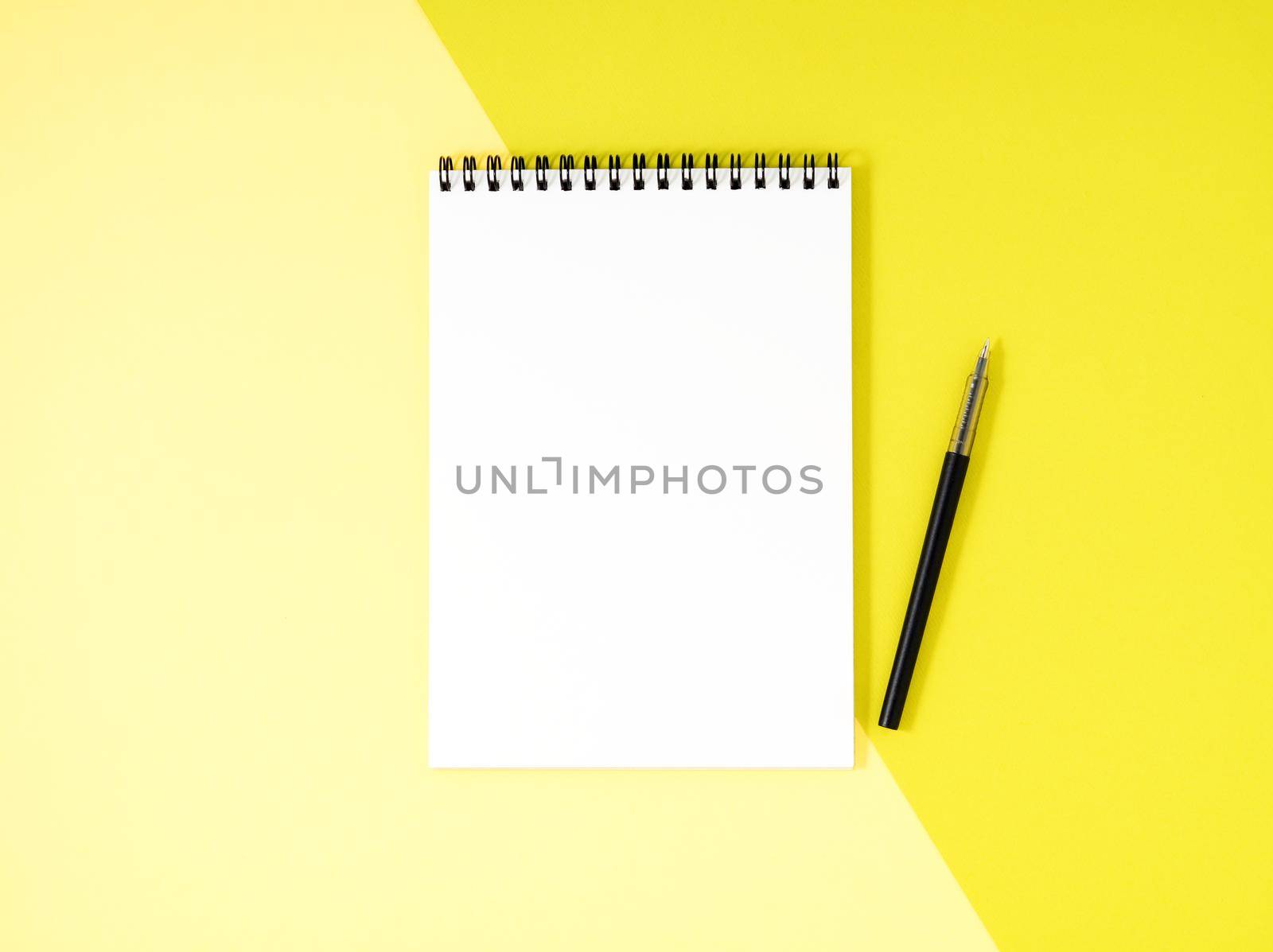 Blank notepad white page on yellow desk, a color background. Top view, empty space for text.