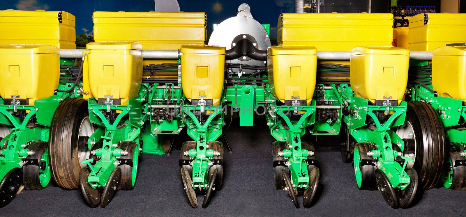 Green with yellow bunkers, modern multi-row planter, wheels, distribution pipes and working mechanisms of a pneumatic agricultural seeder.
