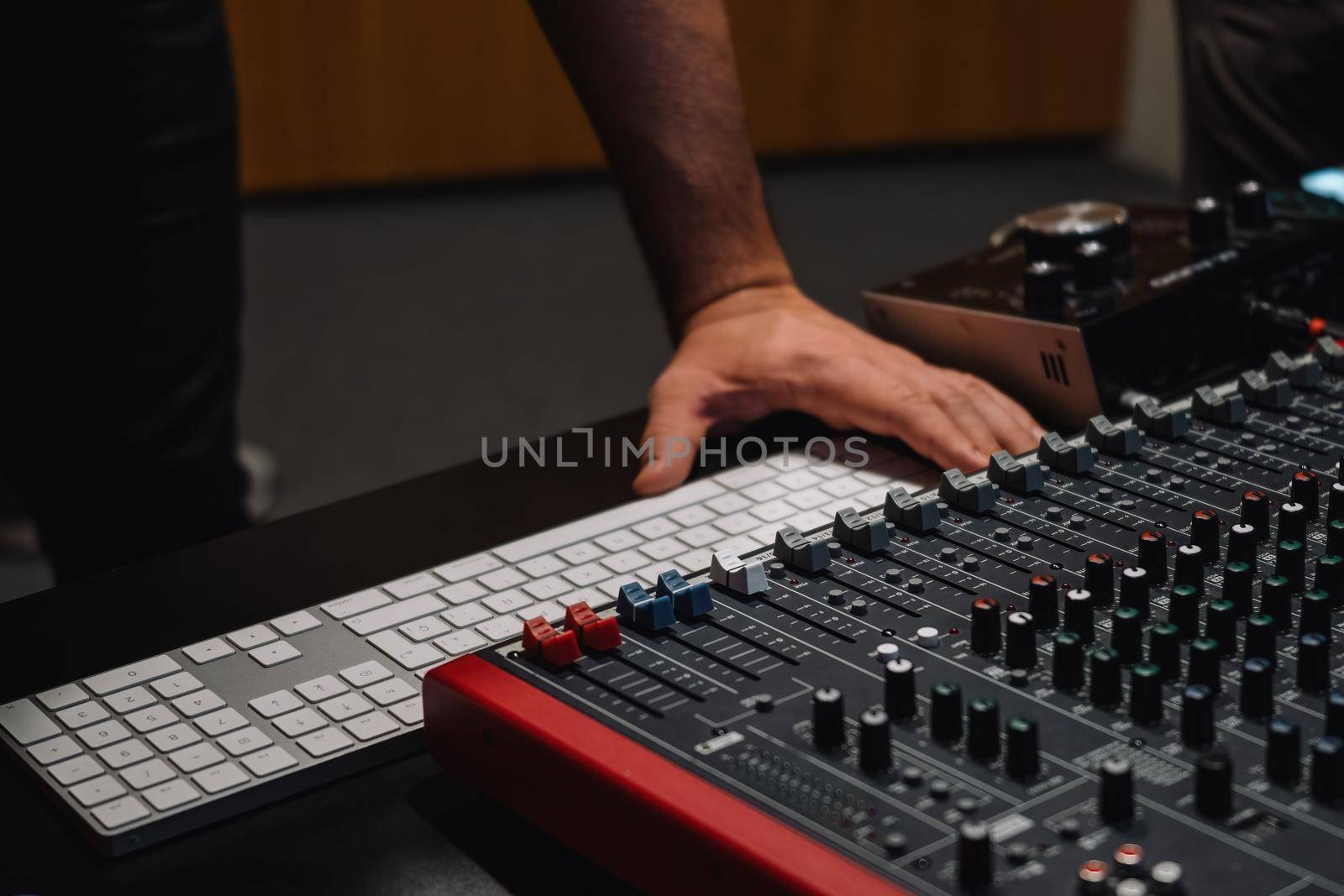 Producer hands at the keyboard in a studio. Musician arranging and mixing music in home studio. Music production concept.
