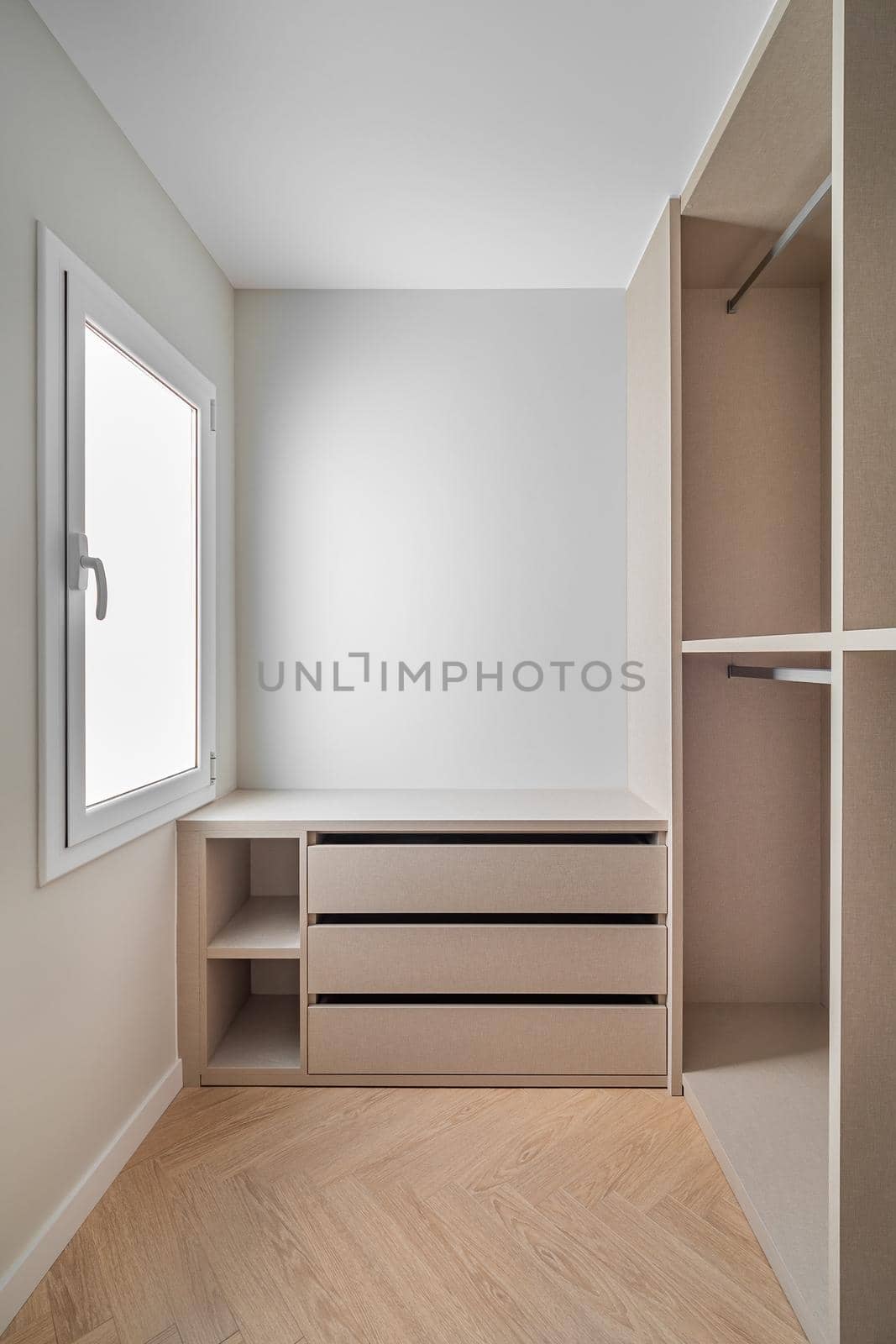 New built-in furniture in a small dressing room. Modern and empty storage room with wardrobe, drawers and plenty of space for hangers