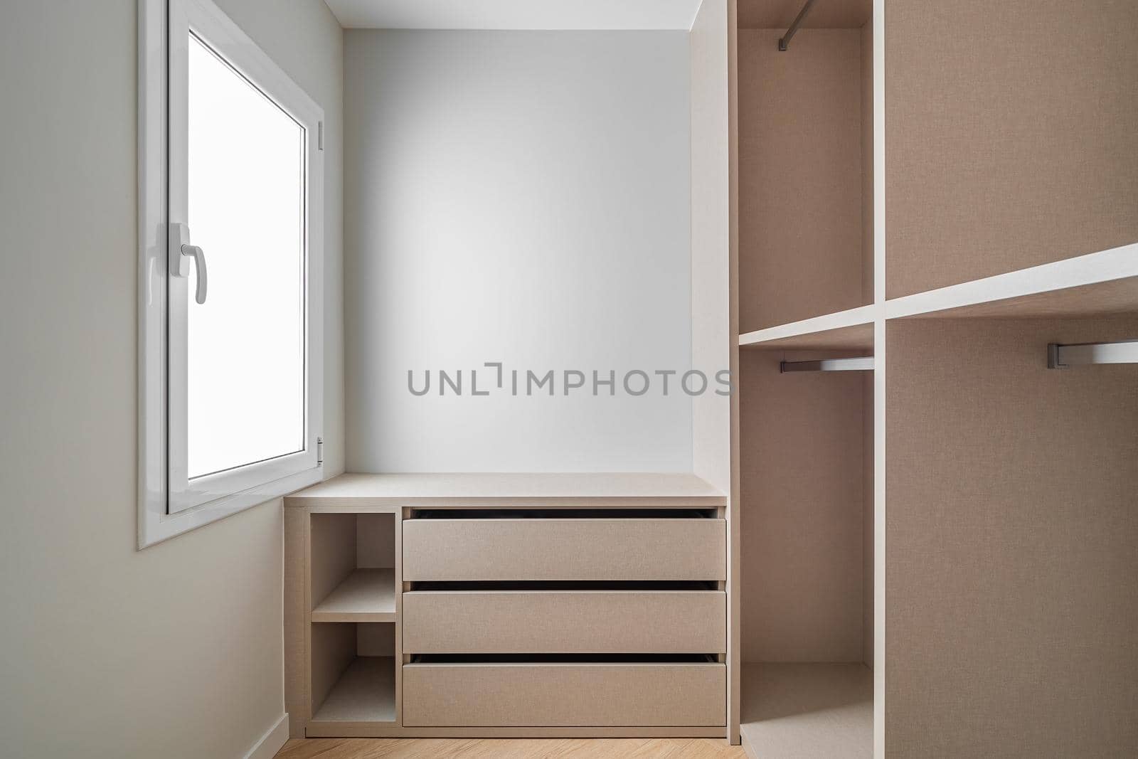 New built-in furniture in a small dressing room. Modern and empty storage room with wardrobe, drawers and plenty of space for hangers