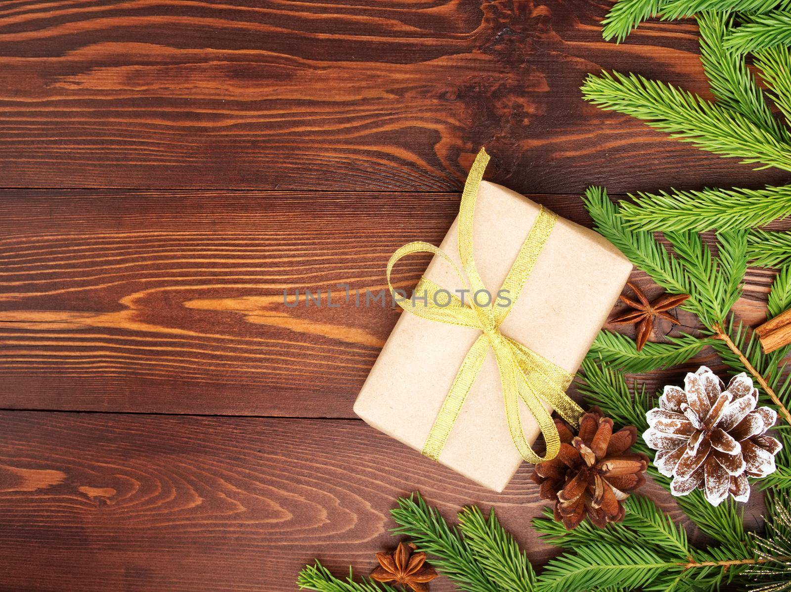 Christmas and Happy New Year dark brown background. Gift Christmas box, fir branches, a wooden table, top view, copy space