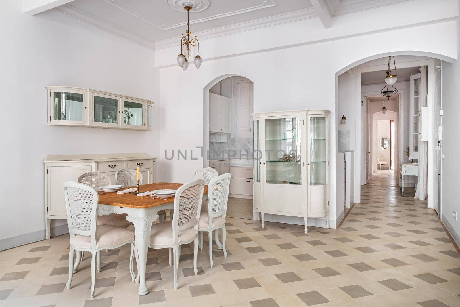 Classic room with dining table, served for two persons, tile floor, light walls and vintage elements of decoration. Beautiful bright interior.