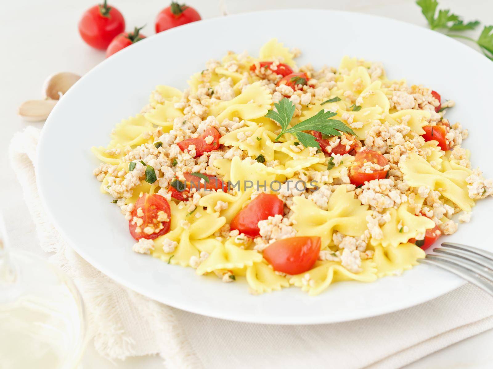 farfalle pasta with tomatoes, chiken meat, parsley on white stone background, low-calorie diet, side view by NataBene
