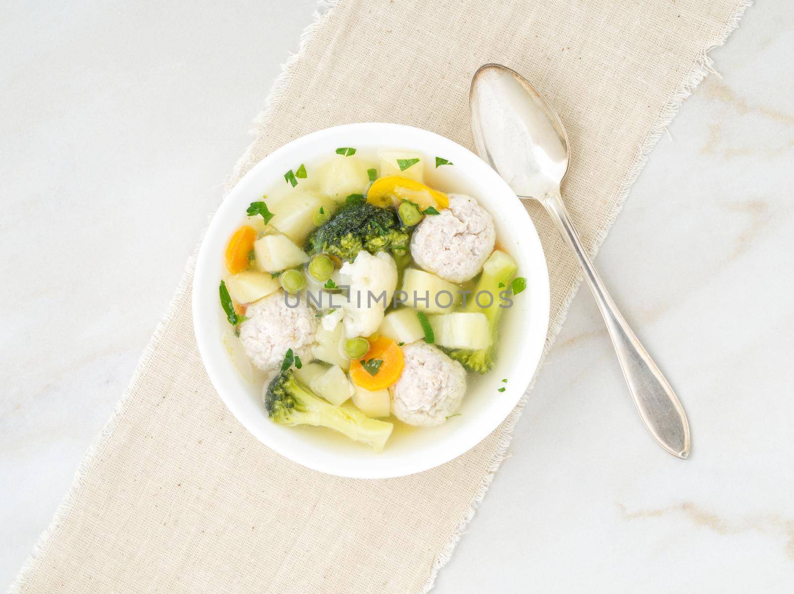 bowl of soup, a cup of broth and vegetables, meatballs made of turkey and a chicken, top view