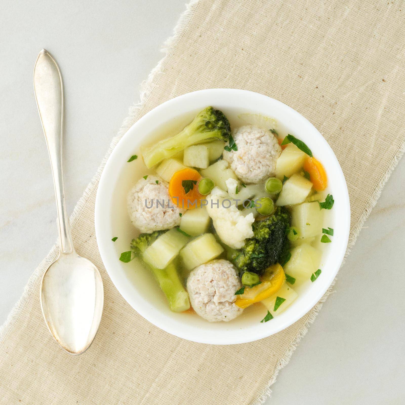 bowl of soup, a cup of broth and vegetables, meatballs made of turkey and a chicken, top view