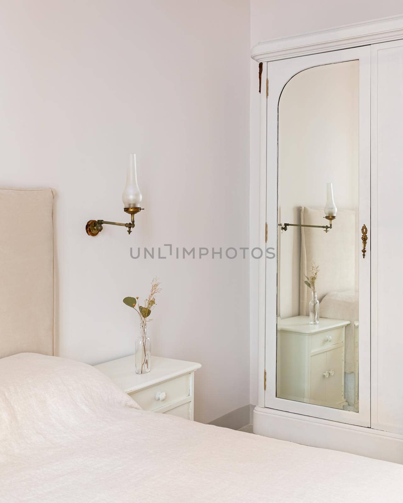 A part of bedroom interior with cozy bed and vintage wardrobe with mirror. Retro and classic style