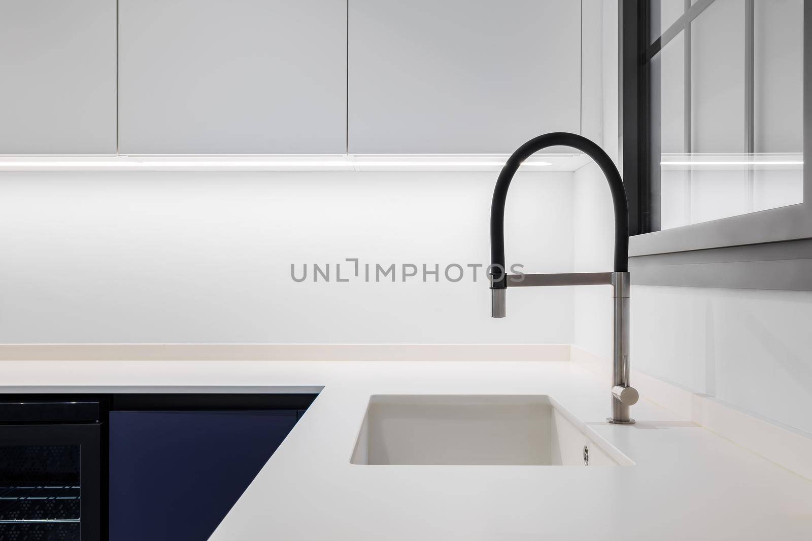 Black faucet with a white sink in a stylish modern kitchen. Minimalism in refurbished apartment. by apavlin