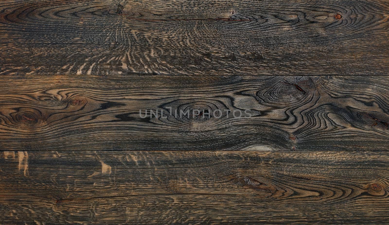Old wooden background from dark brown horizontal planks texture with grains, cracks and knots.