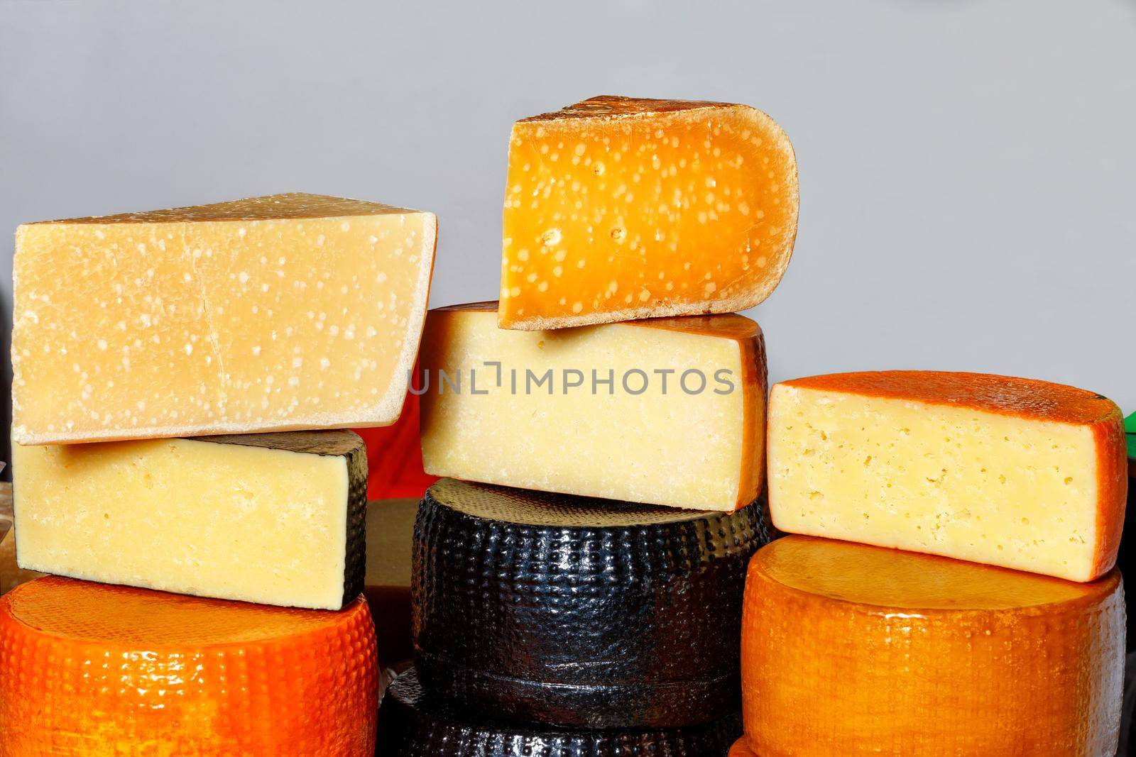 On the counter, cut into pieces and whole heads of homemade cheese of different varieties, on a gray background, copy space. Delicious and healthy food concept.