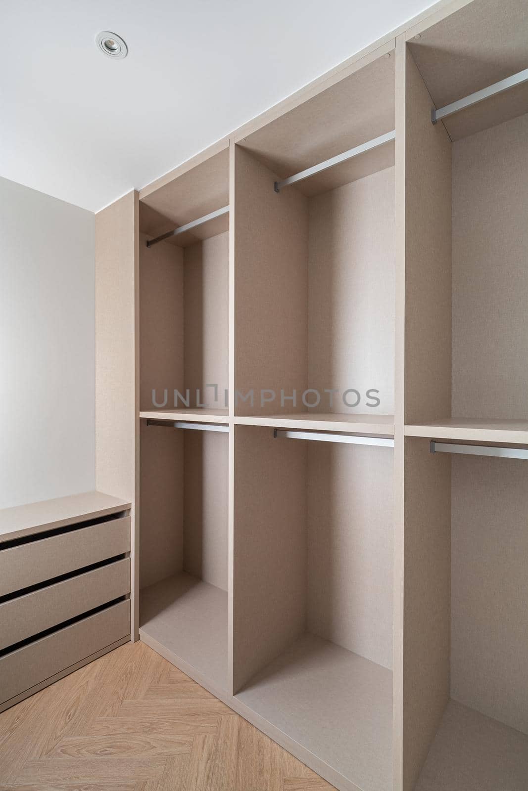 New built-in furniture in a small dressing room. Modern and empty storage room with wardrobe, drawers and plenty of space for hangers. by apavlin