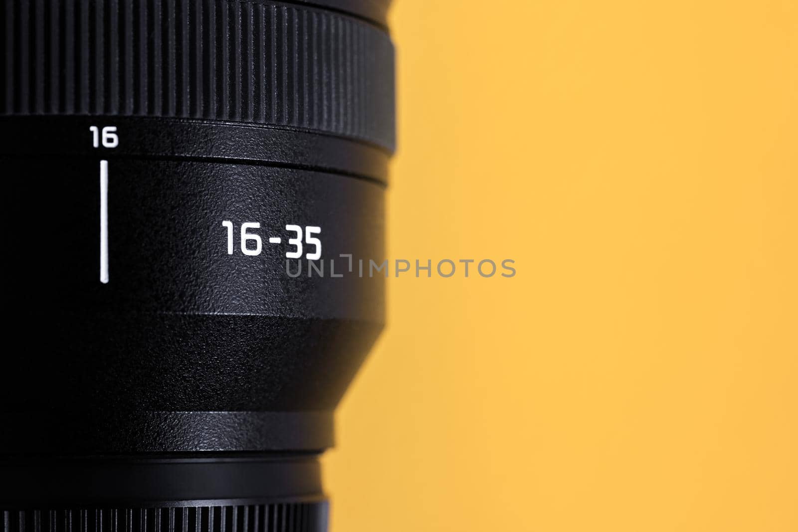 Professional wide angle photo lens with focal distance 16-35mm at yellow background with copy space.