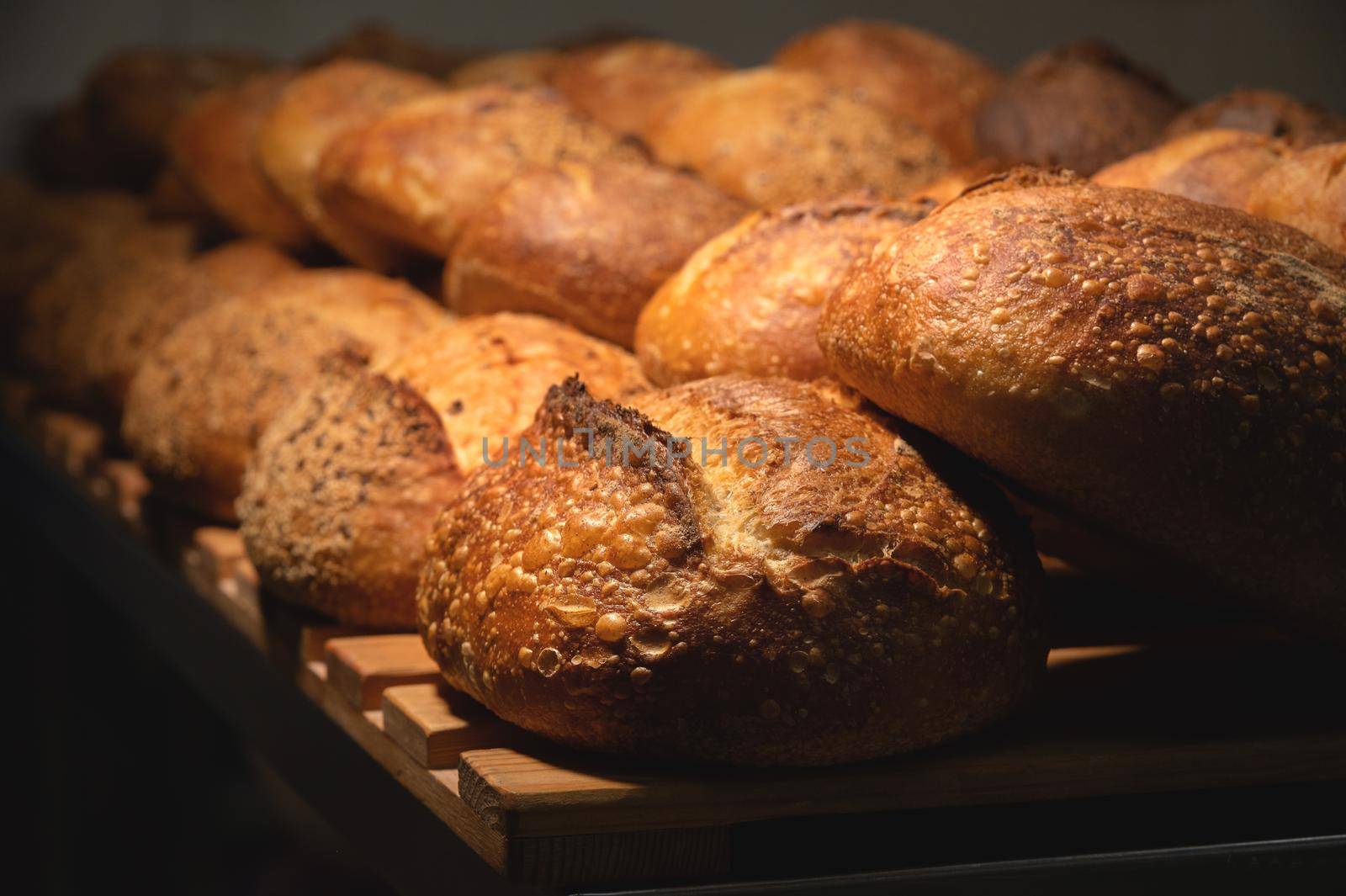 Fresh crispy hot delicious craft artisan bread. Many loaves lie on a wooden pallet by yanik88