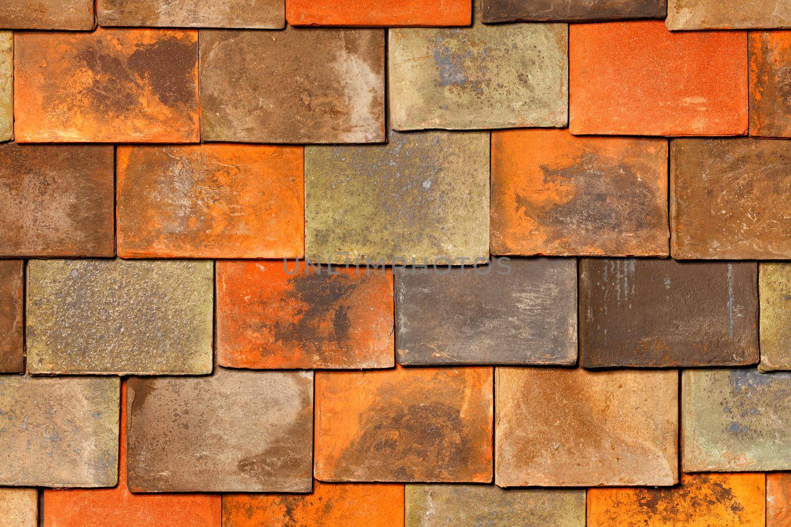 Roofing made of rectangular clay tiles with worn, rusty surfaces. Background and texture, close-up.