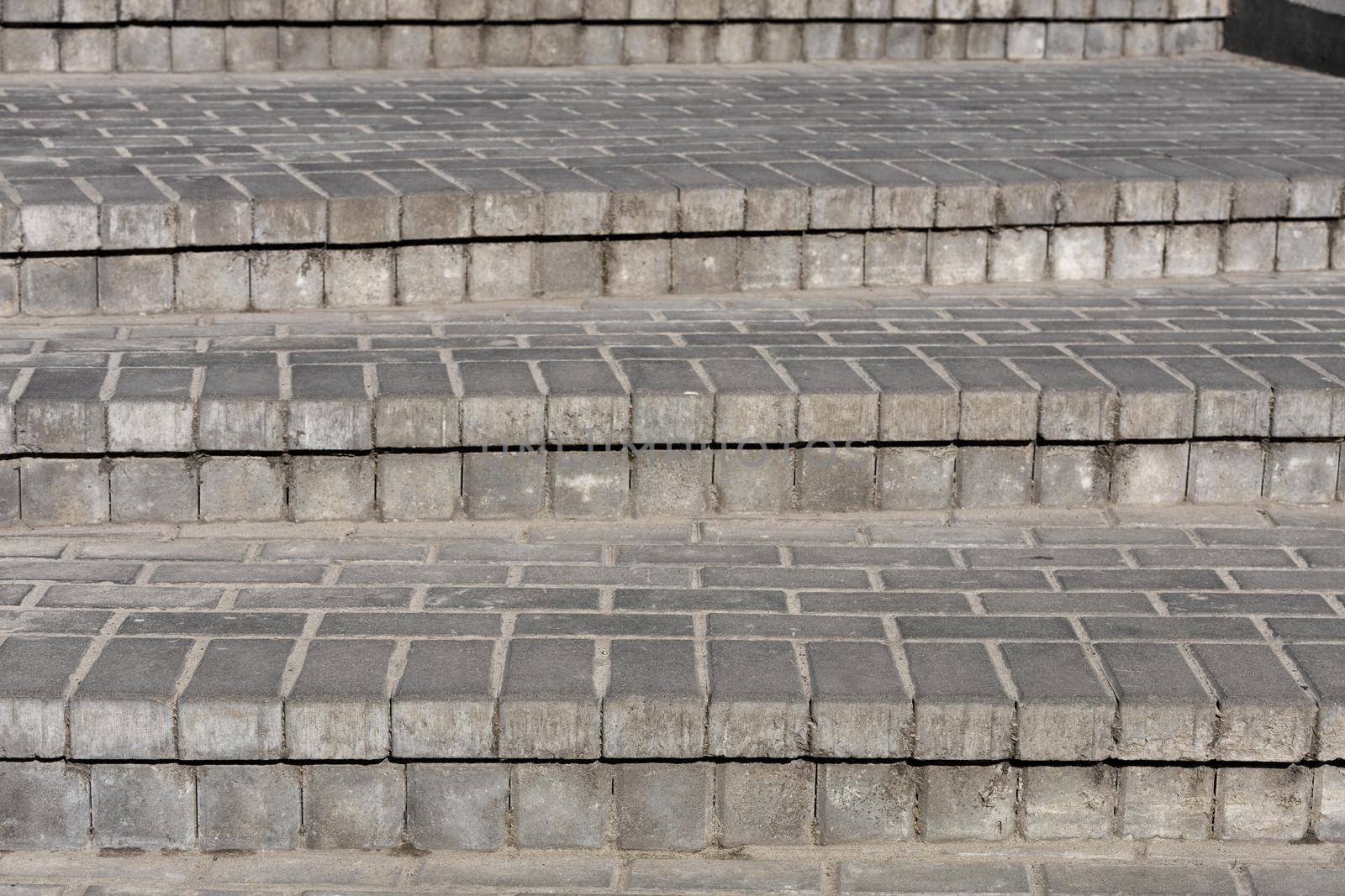 Rows of gray steps of gray paving slabs laid out evenly, consistently and tightly to each other.