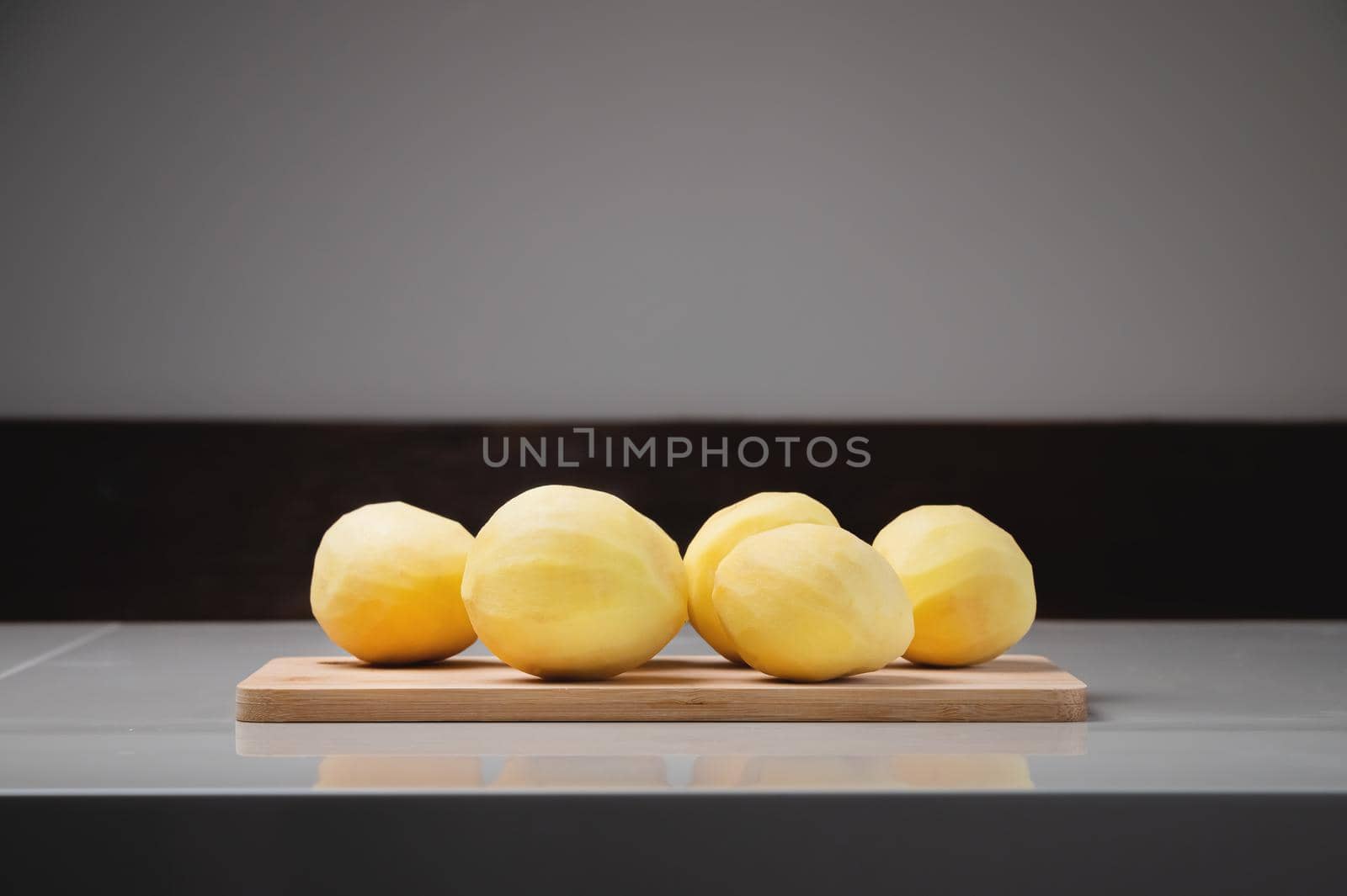 Close-up Several peeled potatoes on a wooden cutting board on a white table