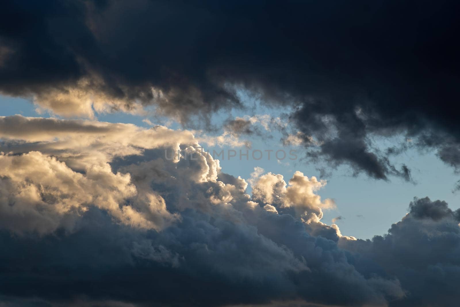 Dramatic sky at sunset twilight with heavy clouds. Opposition of light and darkness