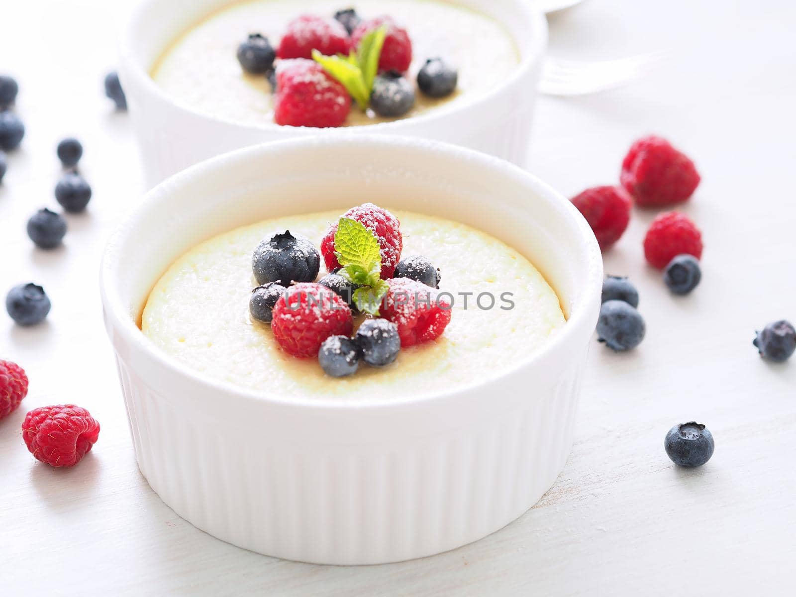 cheesecake decorated with raspberries, blueberries and mint in two ramekin, delicious dessert for a breakfast, side view