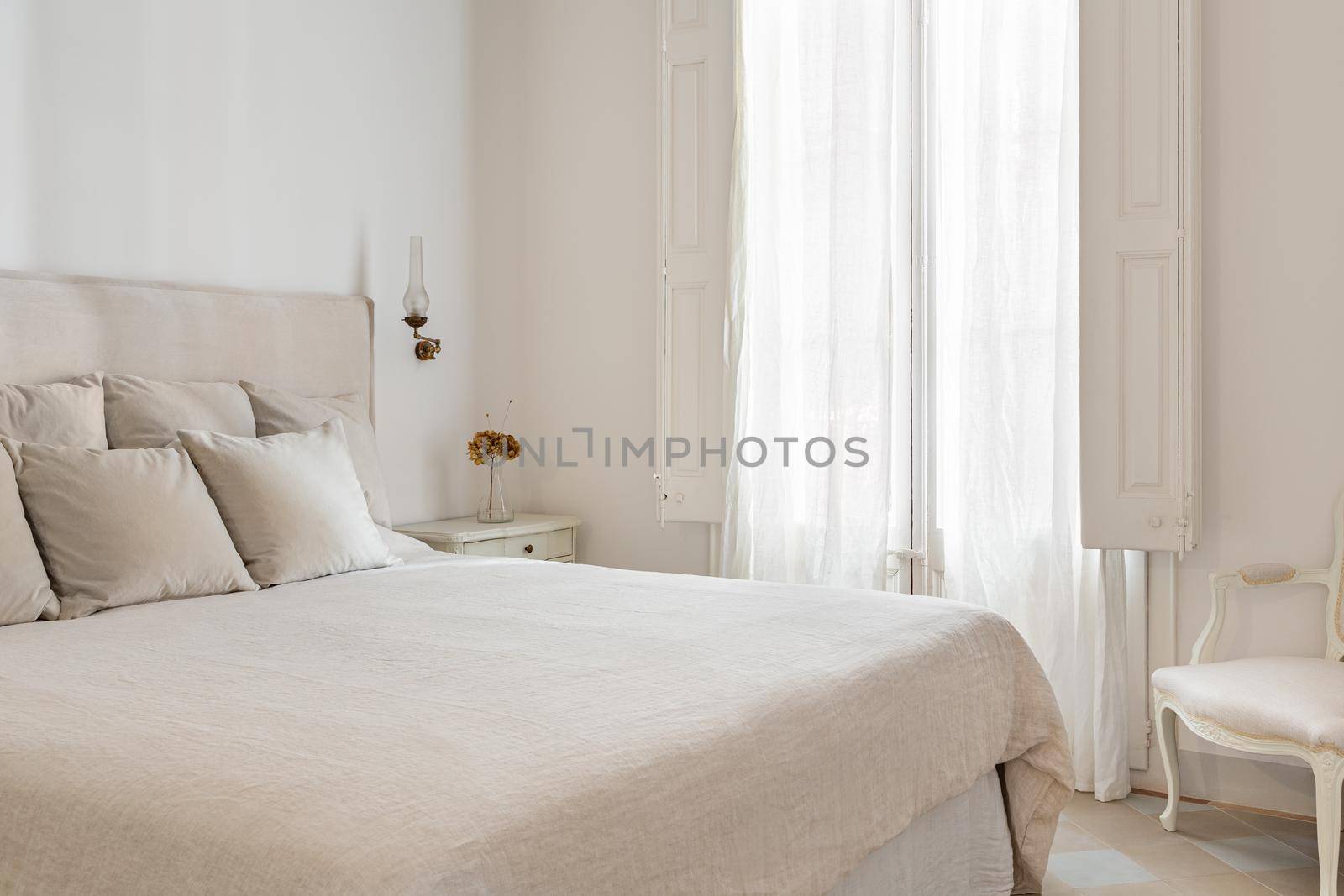Bright bedroom interior, cozy bed with beige linen, dry flowers on a bedside table. Retro and vintage style. by apavlin