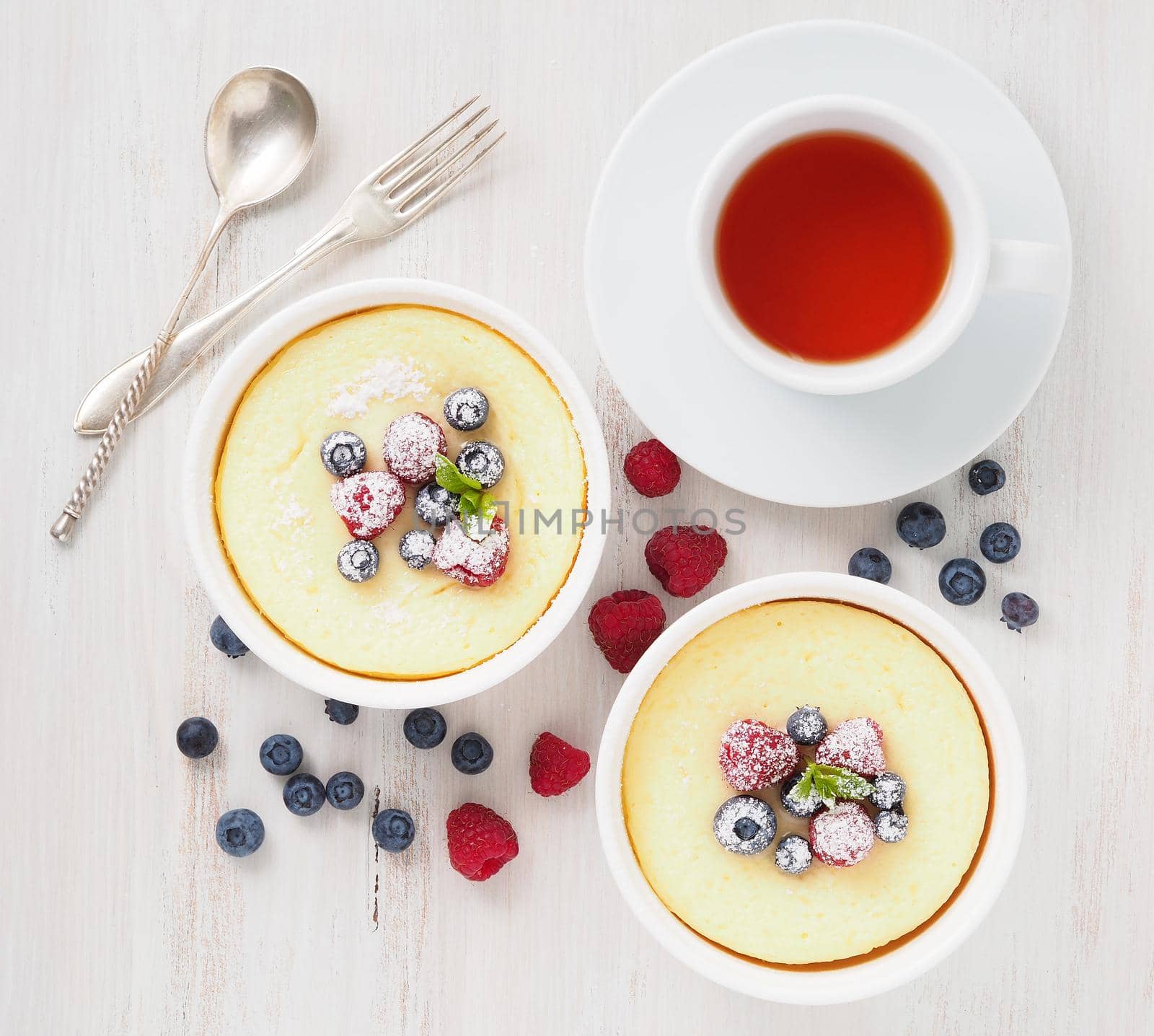 cheesecake decorated with raspberries, blueberries and mint in two ramekin, delicious dessert for a breakfast, top view