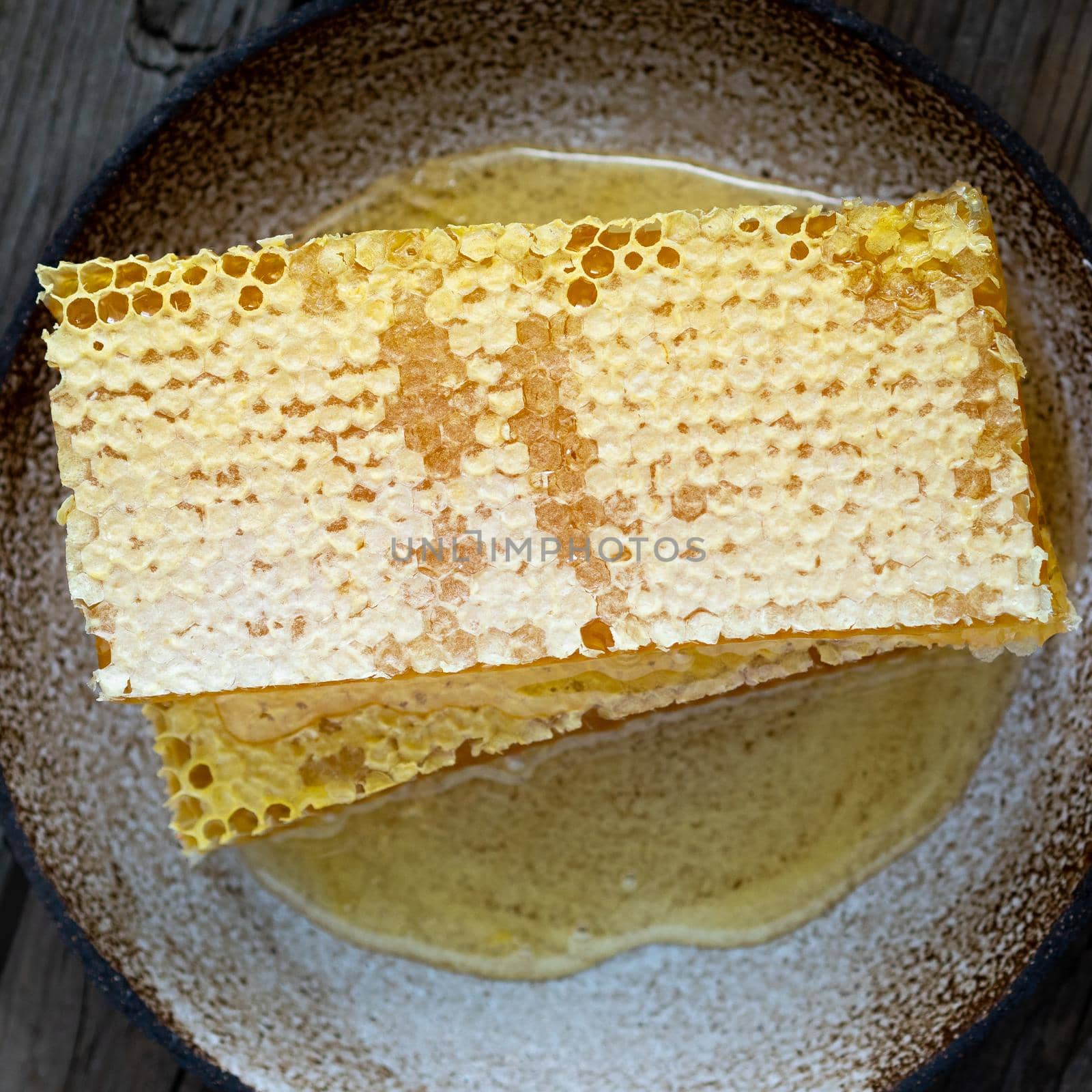 honey in honeycomb, close-up, on a ceramic plate, on a wooden rustic table, top view.