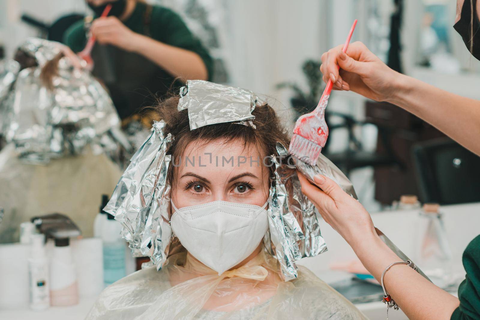 Woman dyes her hair in a barbershop, the process of dyeing her hair with foil. by Niko_Cingaryuk