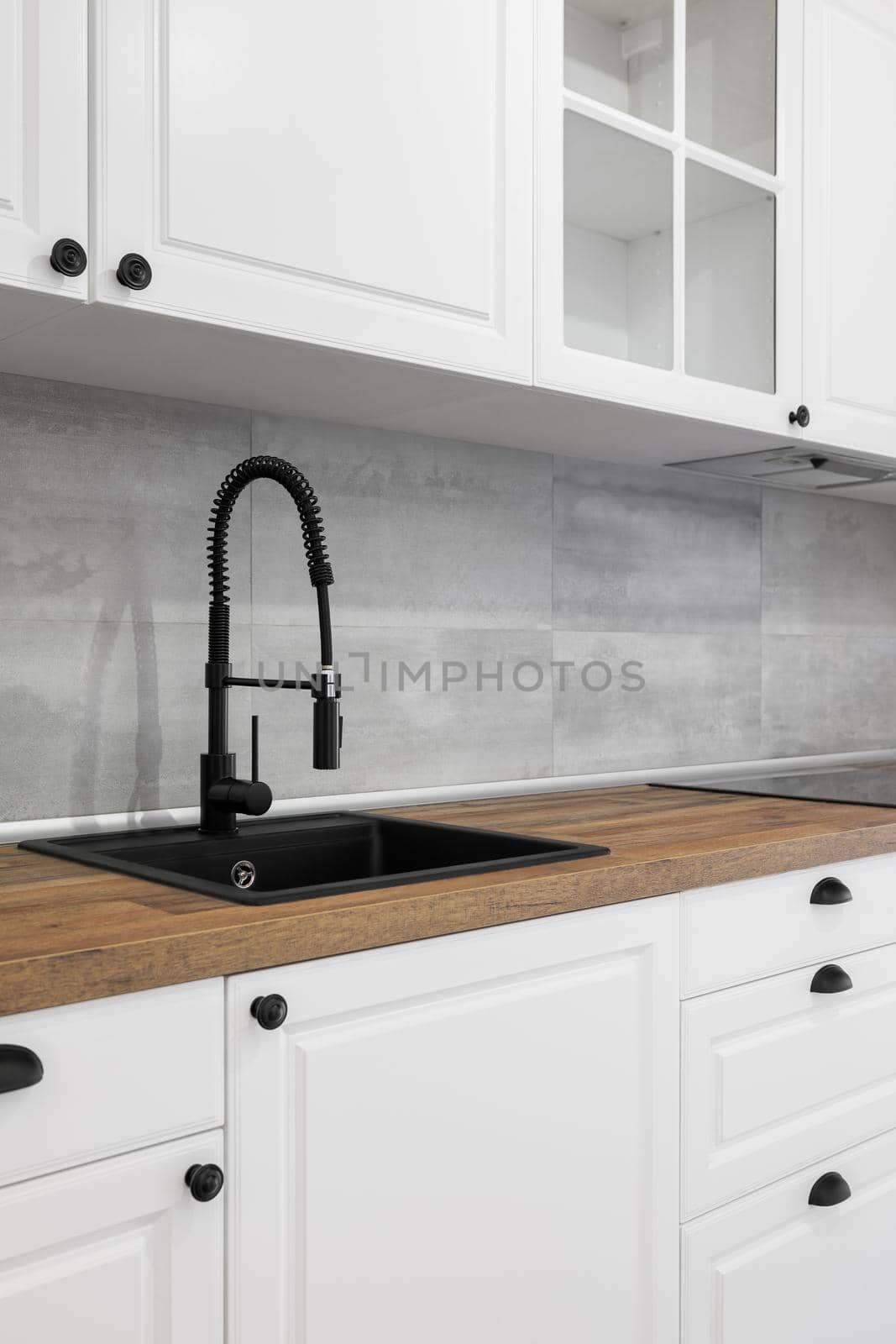 Simple and elegant kitchen with wooden countertop, white cupboards, drawers and black sink. by apavlin
