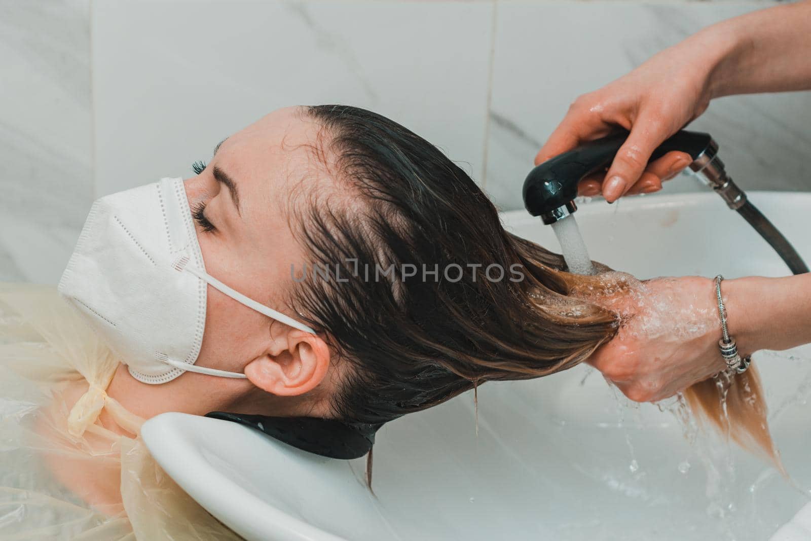 Hairdresser during the world quarantine, washing the head in a beauty salon, a client in a mask. new
