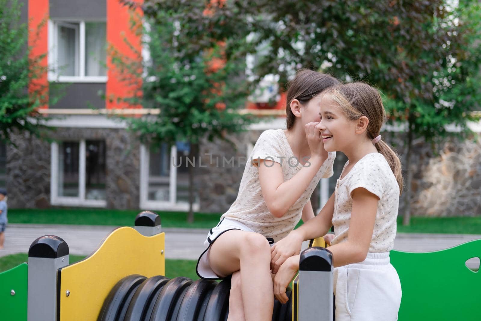 sisterhood, friendship. two charming teen girls having fun on a modern playground. sister, bffs communication by oliavesna