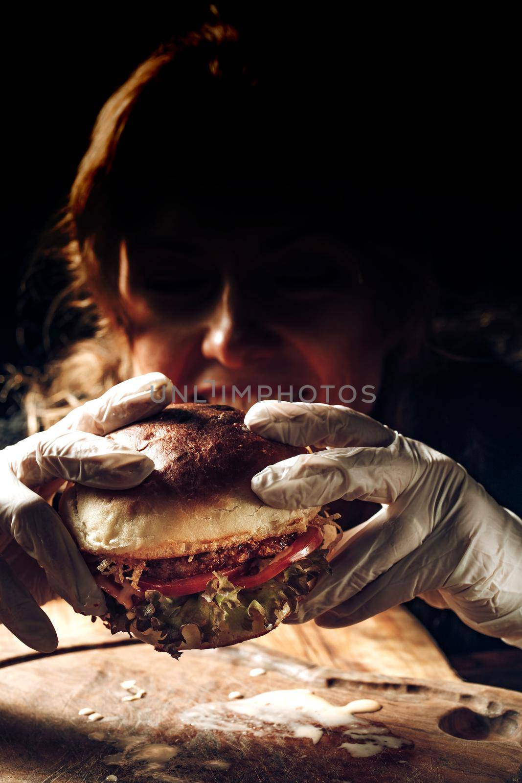 A girl holds a hamburger in her hands in gloves. High quality photo