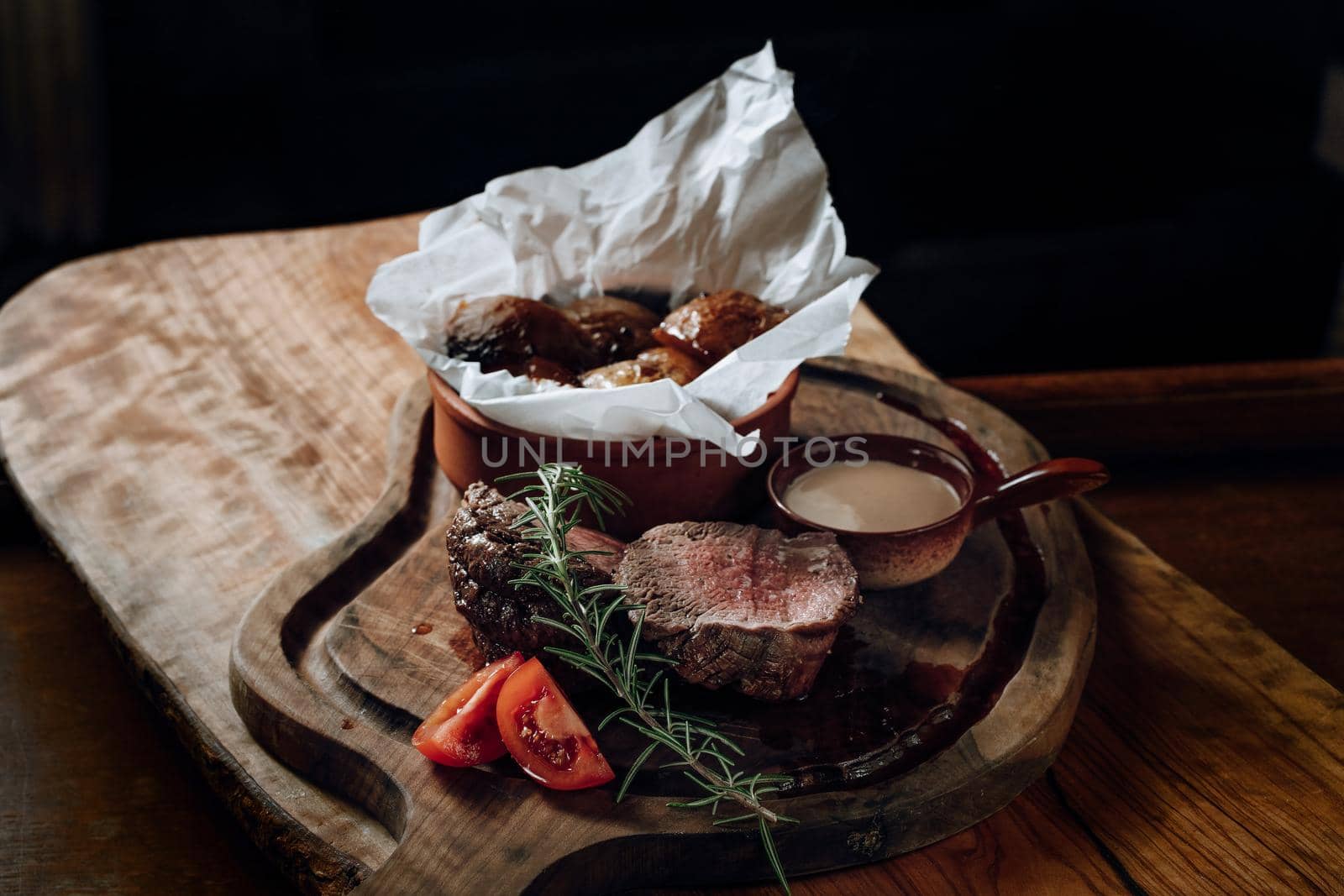 Juicy delicious steak with sauce and baked potatoes on a wooden surface. High quality photo