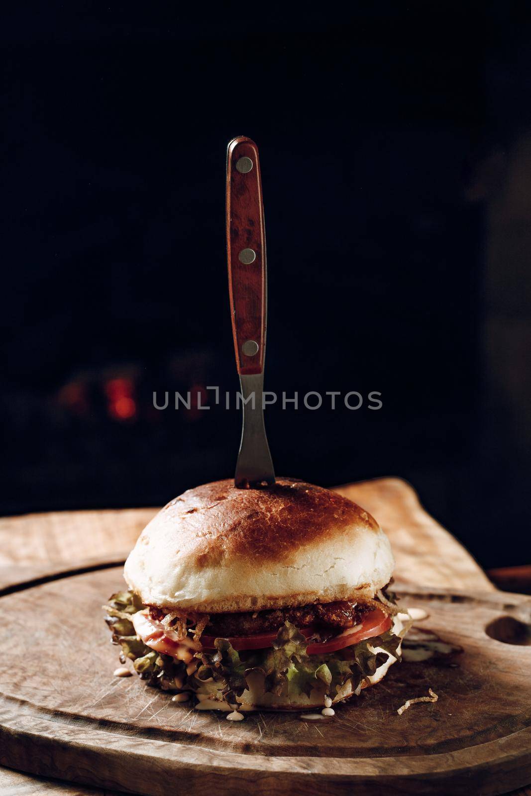 Juicy hamburger on a wooden stand on a black background. High quality photo