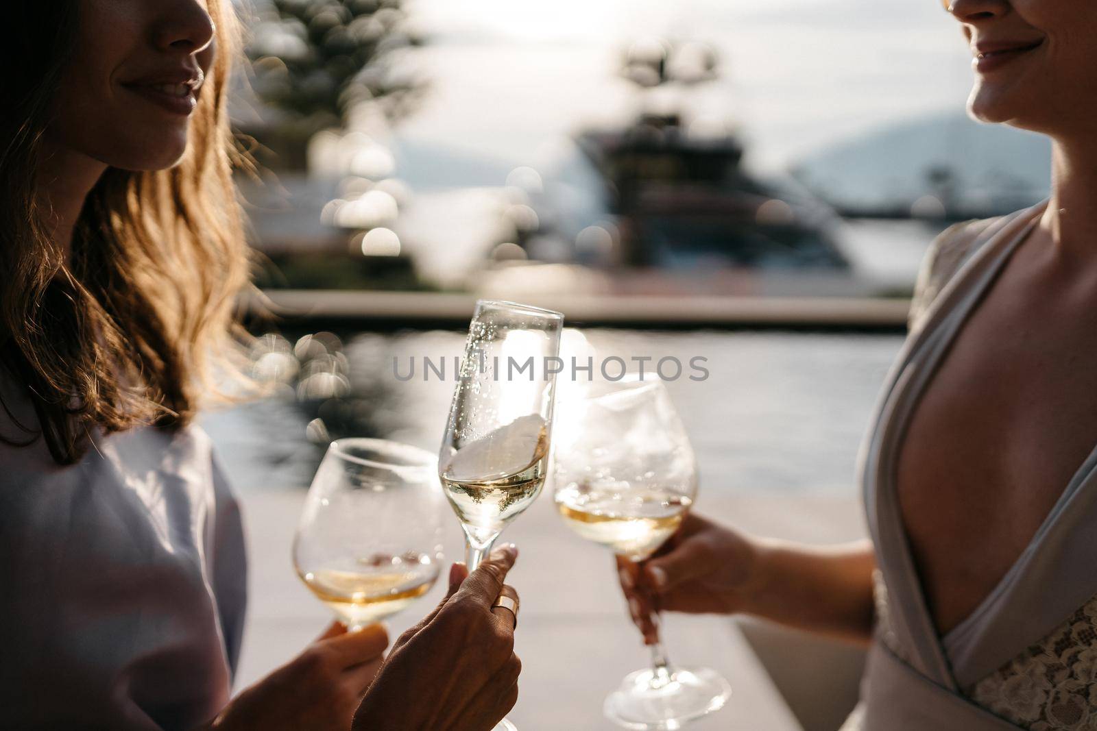 Girls with glasses in their hands drink at sunset. High quality photo